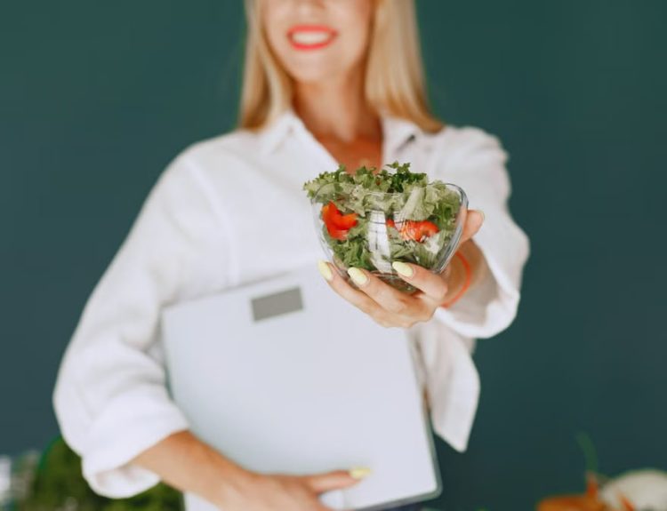 A woman with a vibrant smile offering a fresh salad bowl, promoting healthy eating.