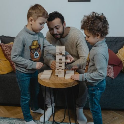 Father and sons enjoying a fun Jenga game in a cozy living room setting.