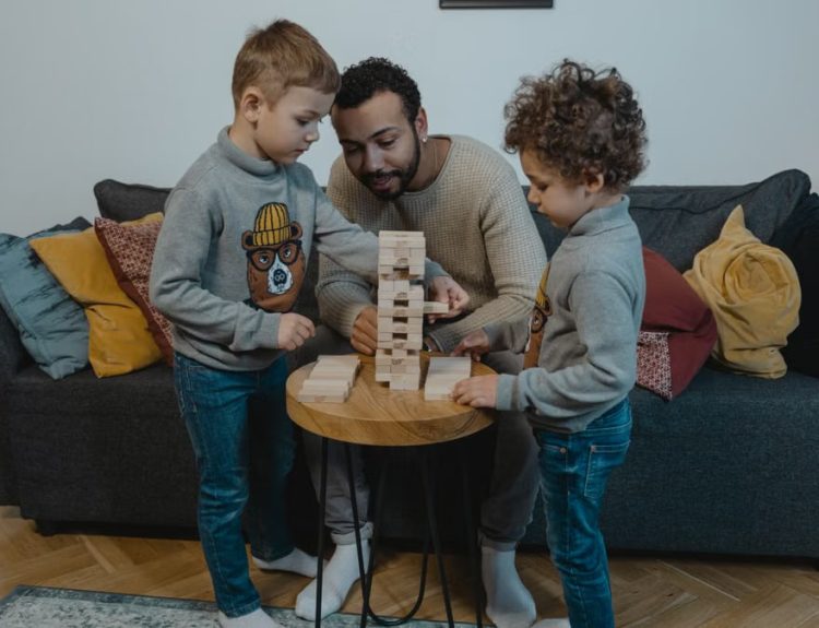 Father and sons enjoying a fun Jenga game in a cozy living room setting.