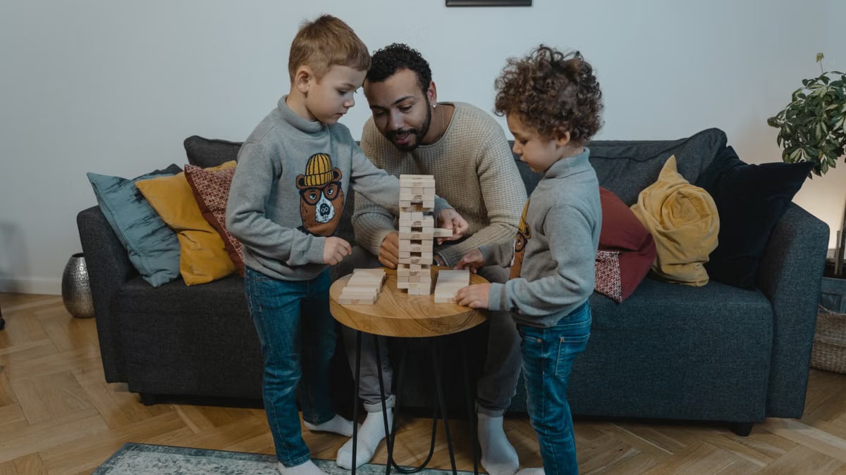 Father and sons enjoying a fun Jenga game in a cozy living room setting.