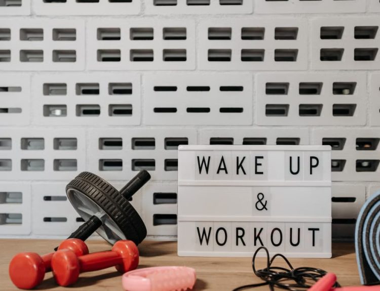 Fitness gear and motivational sign in home gym setup against a brick wall.